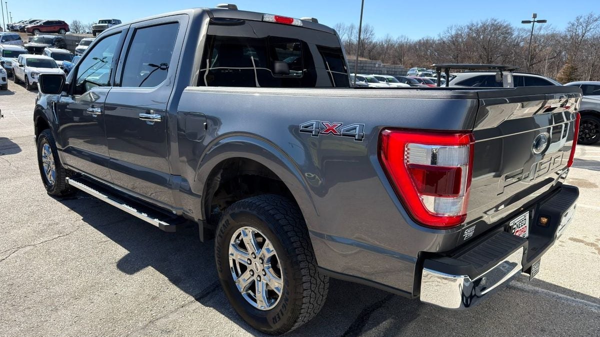 Rear three-quarter view of a gray 2023 Ford F-150 Lariat 4x4 on the used vehicle lot at Dennis Sneed Ford in Gower, MO