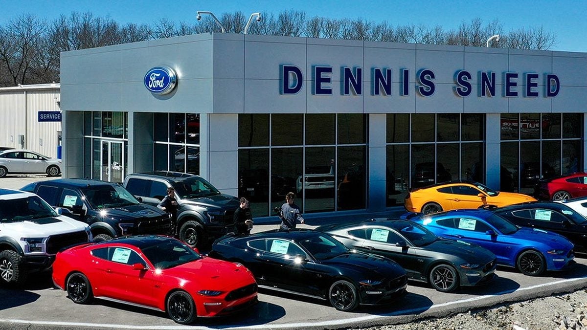 Dennis Sneed Ford dealership in Gower, Missouri, with the service building at left and Ford trucks and Mustangs parked out front